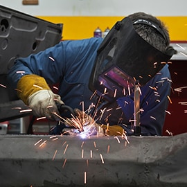 Teknisyen fabrikada metal tabakaları bir araya getirerek kaynak yaparken kıvılcımlar uçuşur