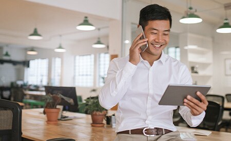 Telefonla konuşup tablete bakan ve gülümseyen bir iş insanı fotoğrafı.
